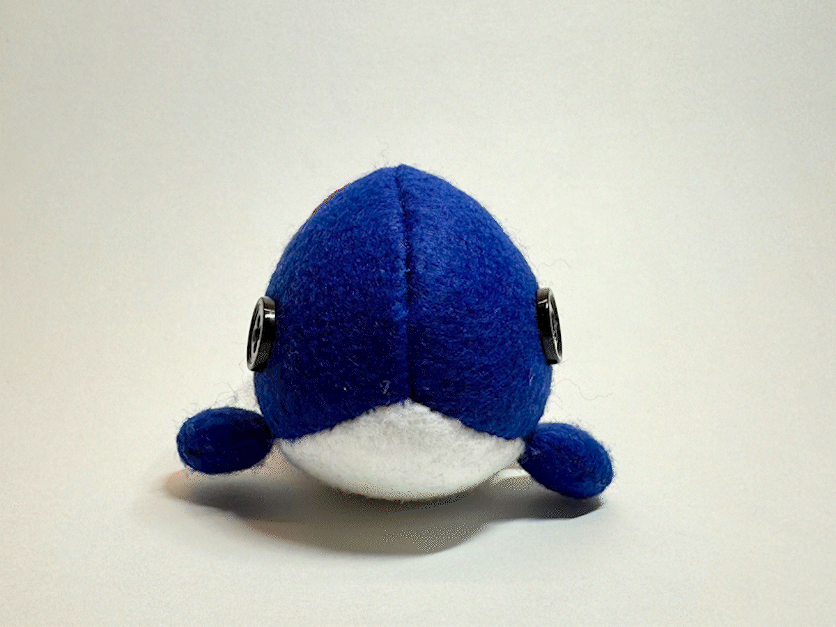 Stopmotion of a small whale stuffed animal getting rotated around 360 degrees.