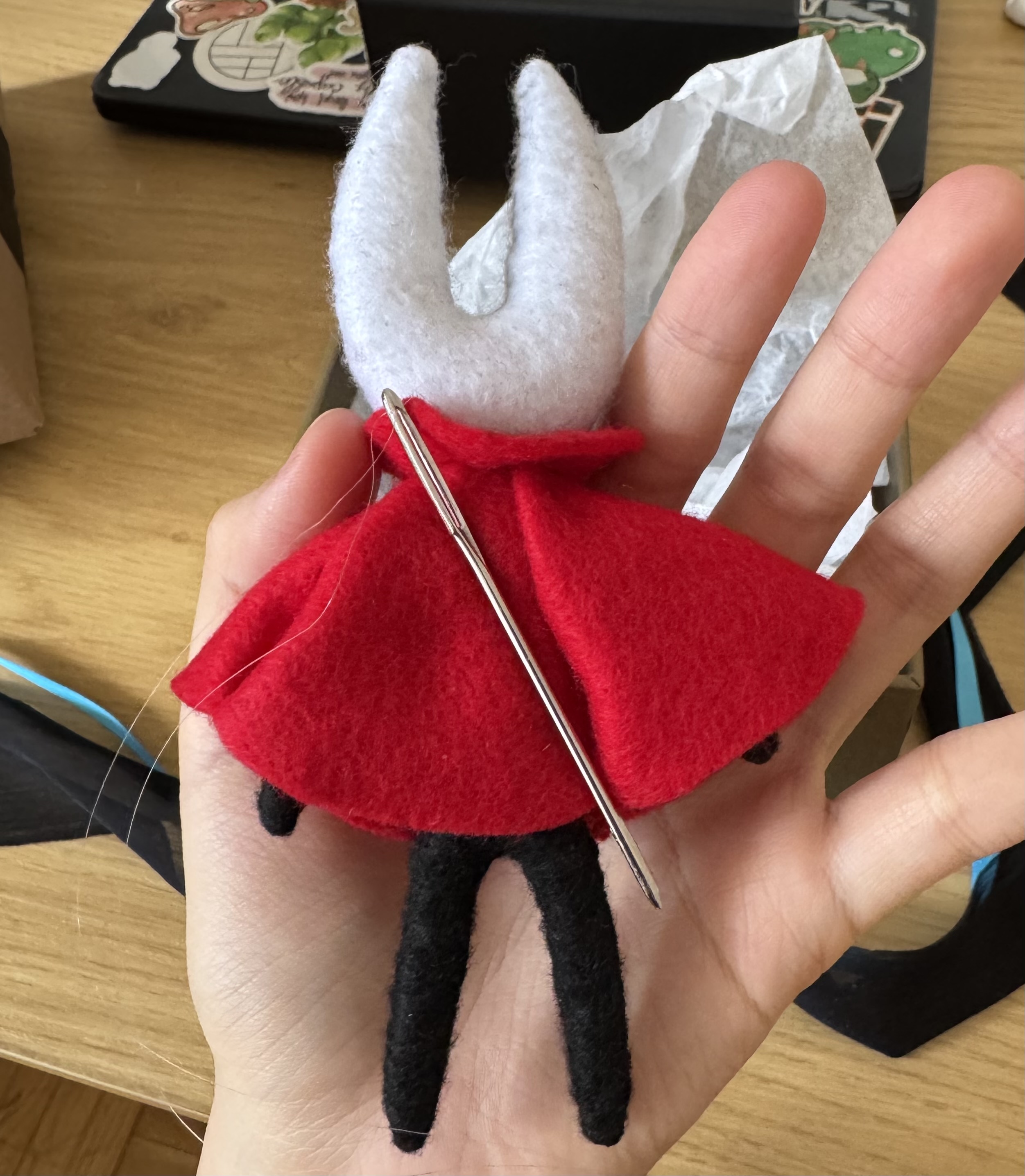 The back side of felt Hornet from Hollow Knight held in the artist's left hand