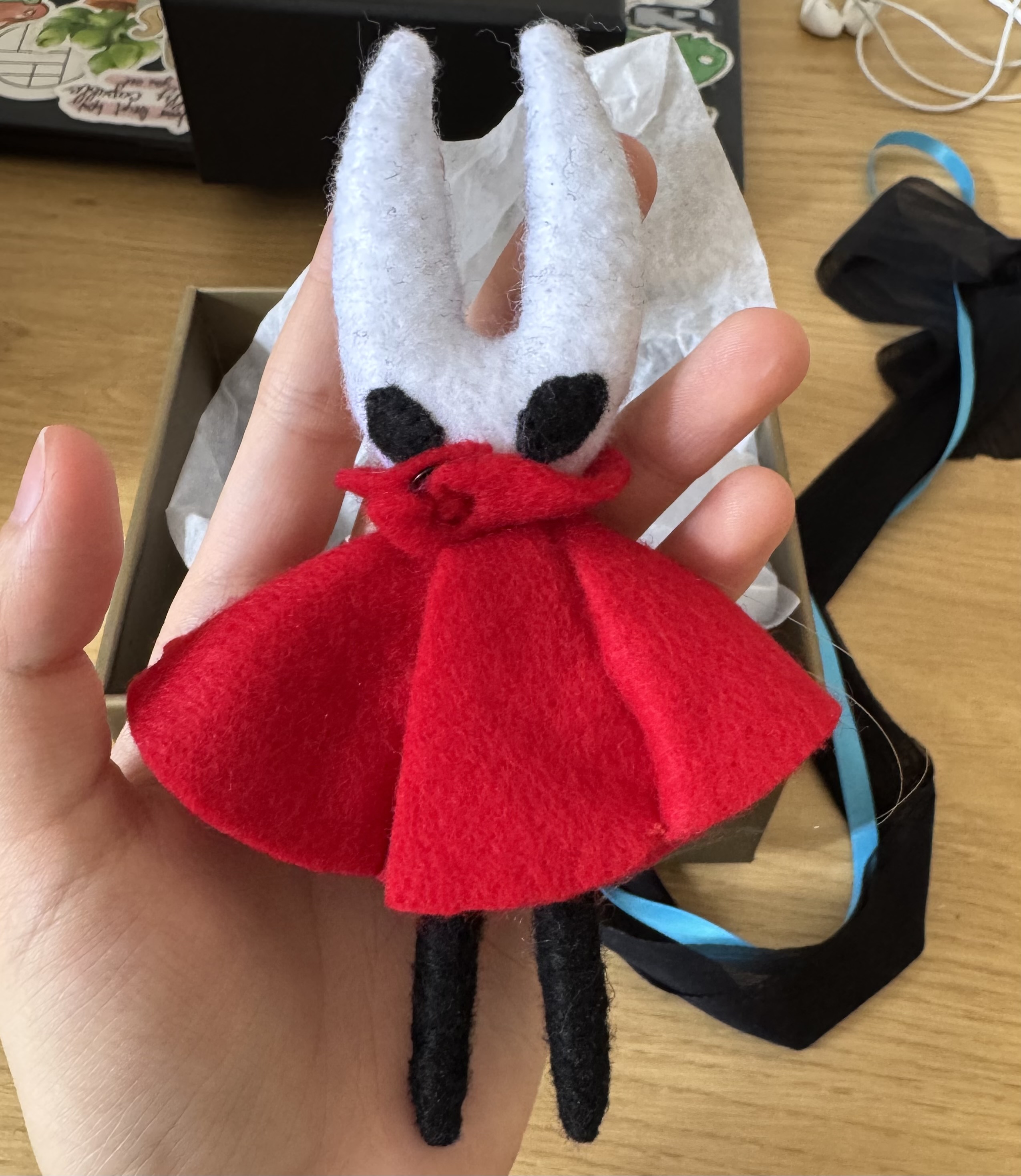 The front side of felt Hornet from Hollow Knight held in the artist's left hand