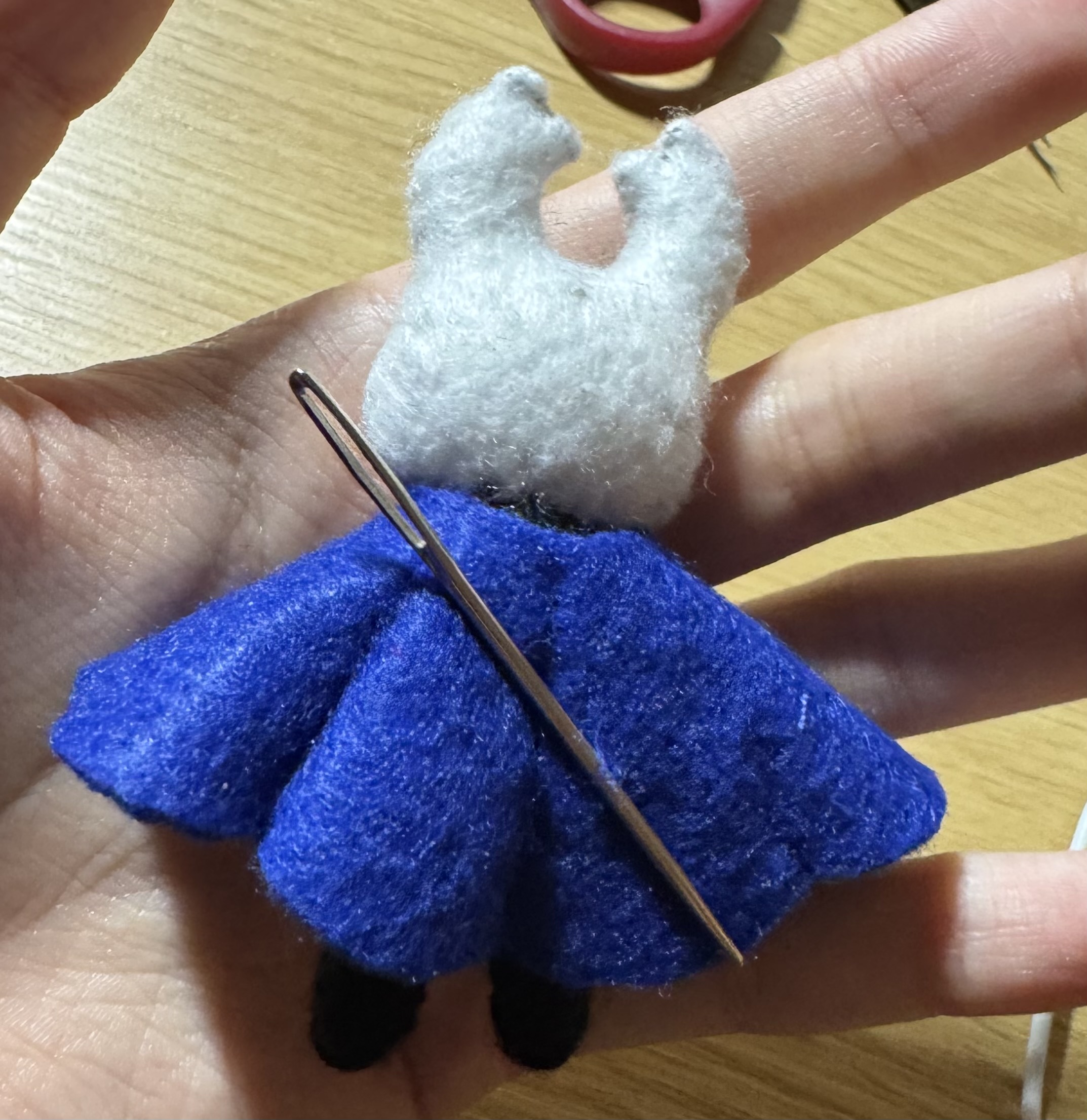 The back side of the felt Knight from Hollow Knight held in the artist's left hand
