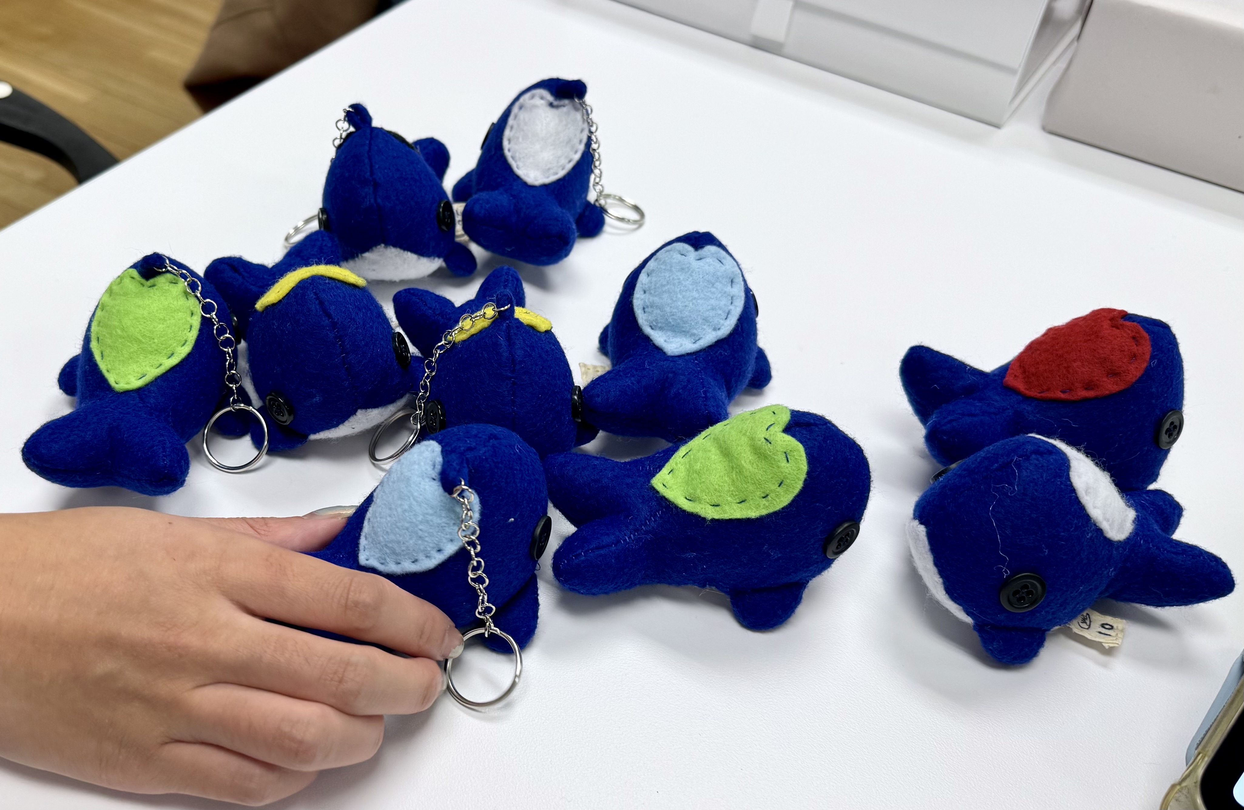 An image of a group of Heart Whales on a table while a hand reaches in to grab one.